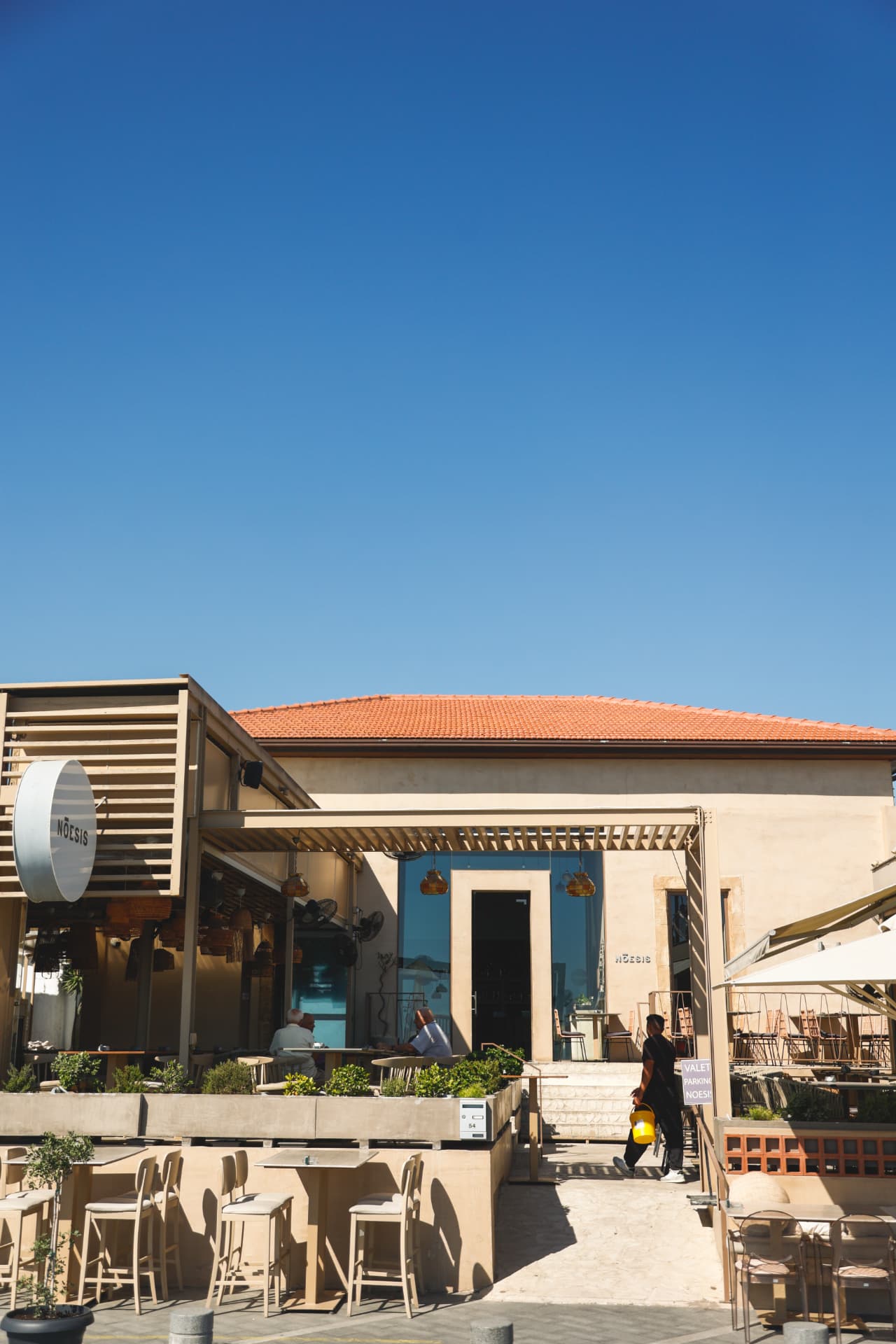 The Nōesis entrance and terrace patio on a sunny day